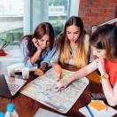 Female office workers planning vacation using map.
