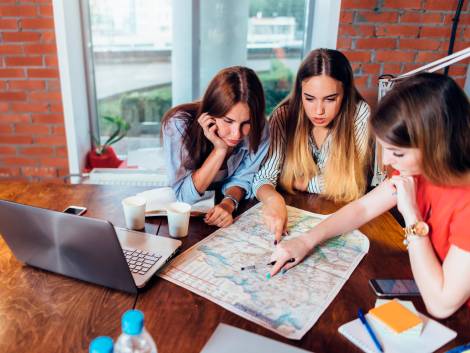 Female office workers planning vacation using map.