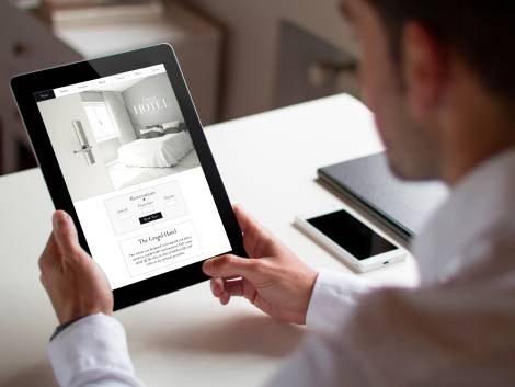 bussinessman at office holding a tablet showing booking hotel website. All screen graphics are made up.