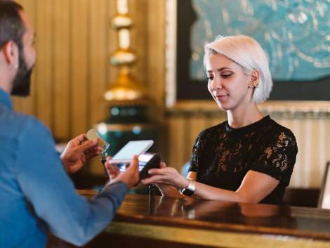 A businessman is making a contactless payment at a hotel reception.